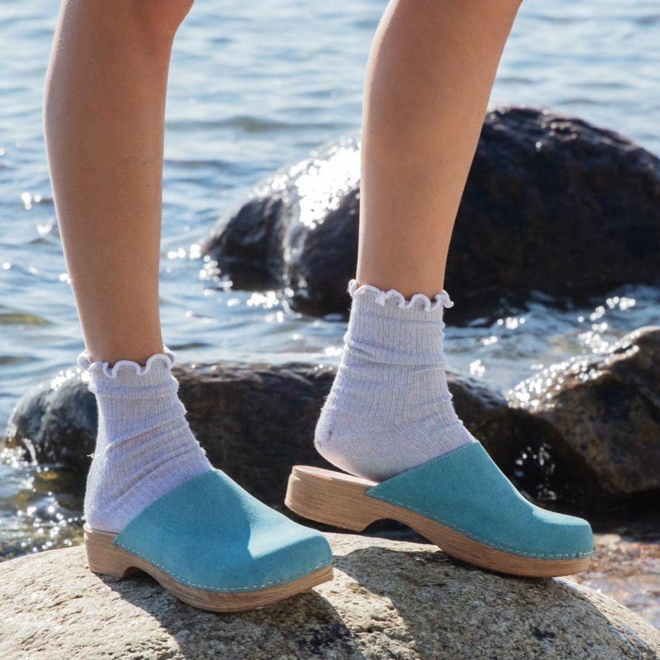 Helena turquoise clogs on model by the sea Calou Stockholm