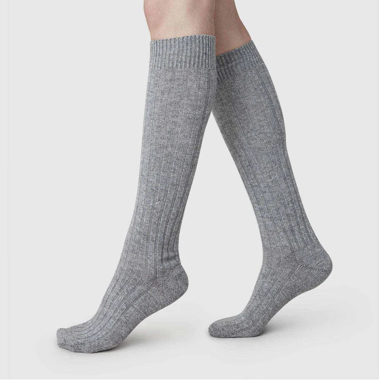 Gray knee-high socks worn by a person on a light gray background