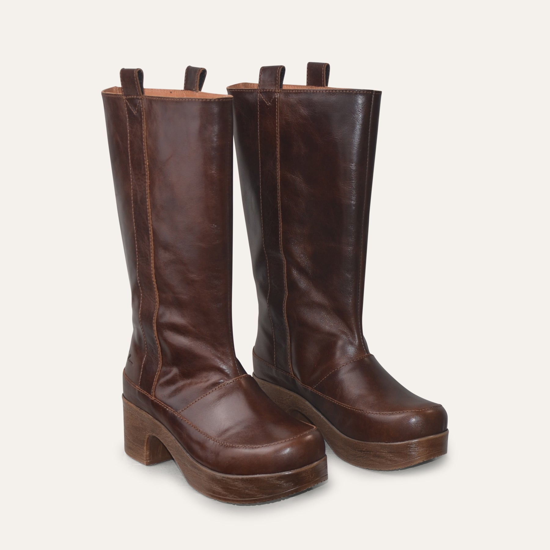 Pair of brown leather knee-high boots on a light gray background