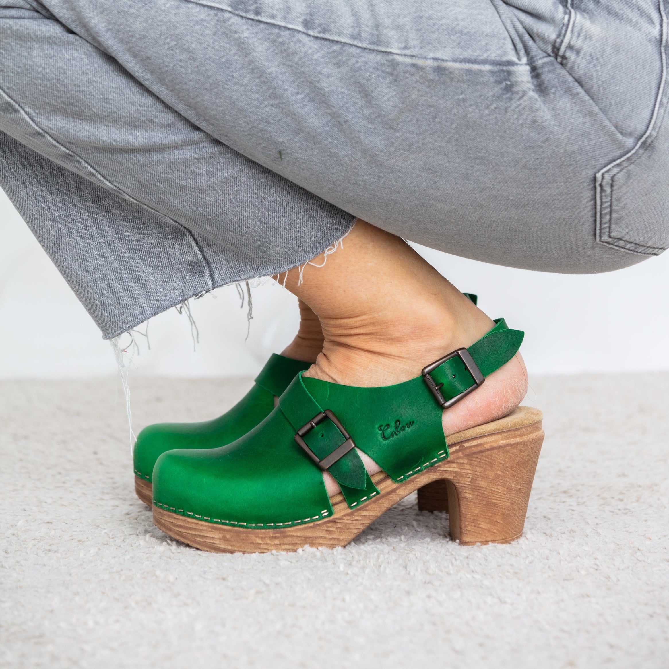 Astrid green leather clogs with heel on model grey jeans Calou Stockholm