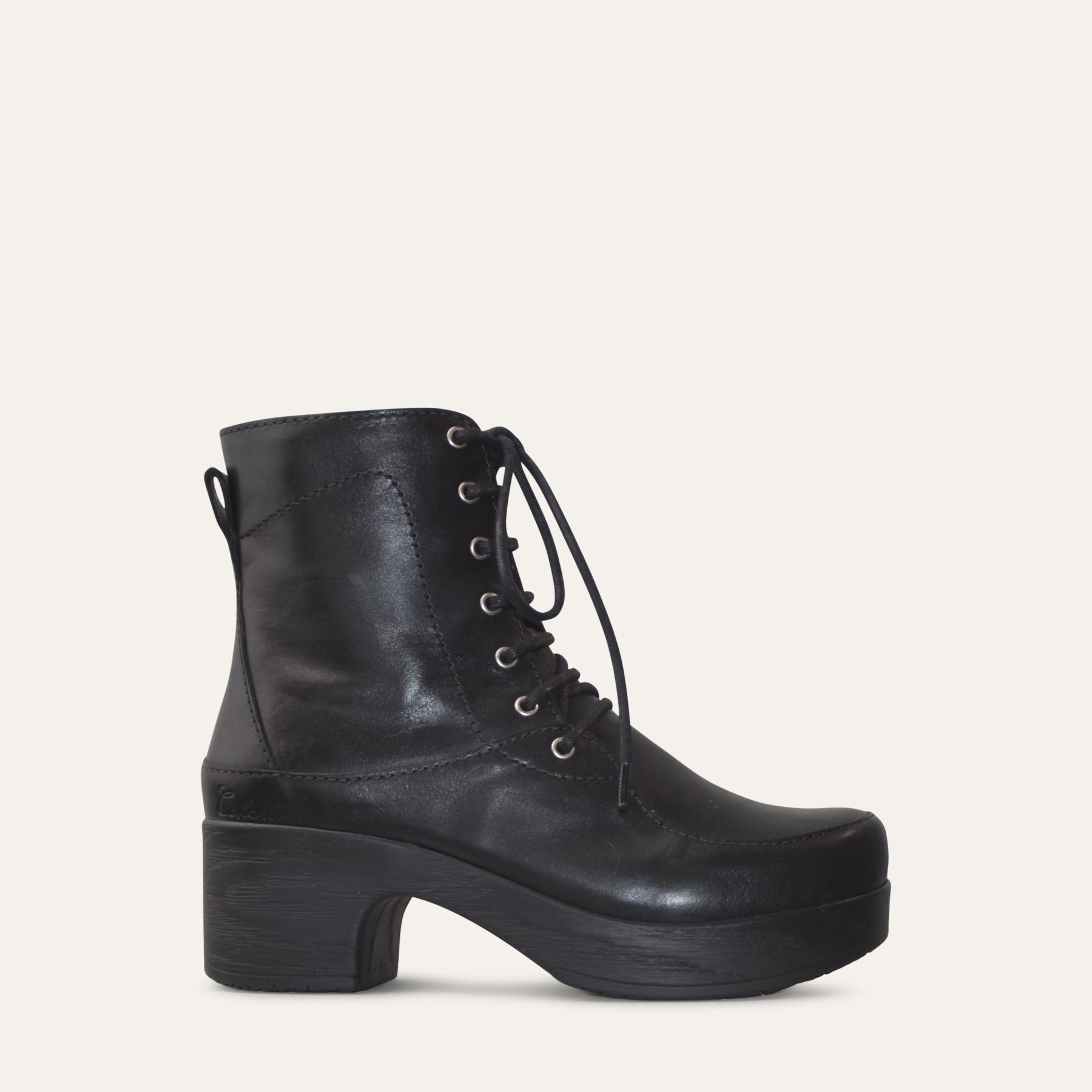 Black leather boot with a block heel on a light gray background