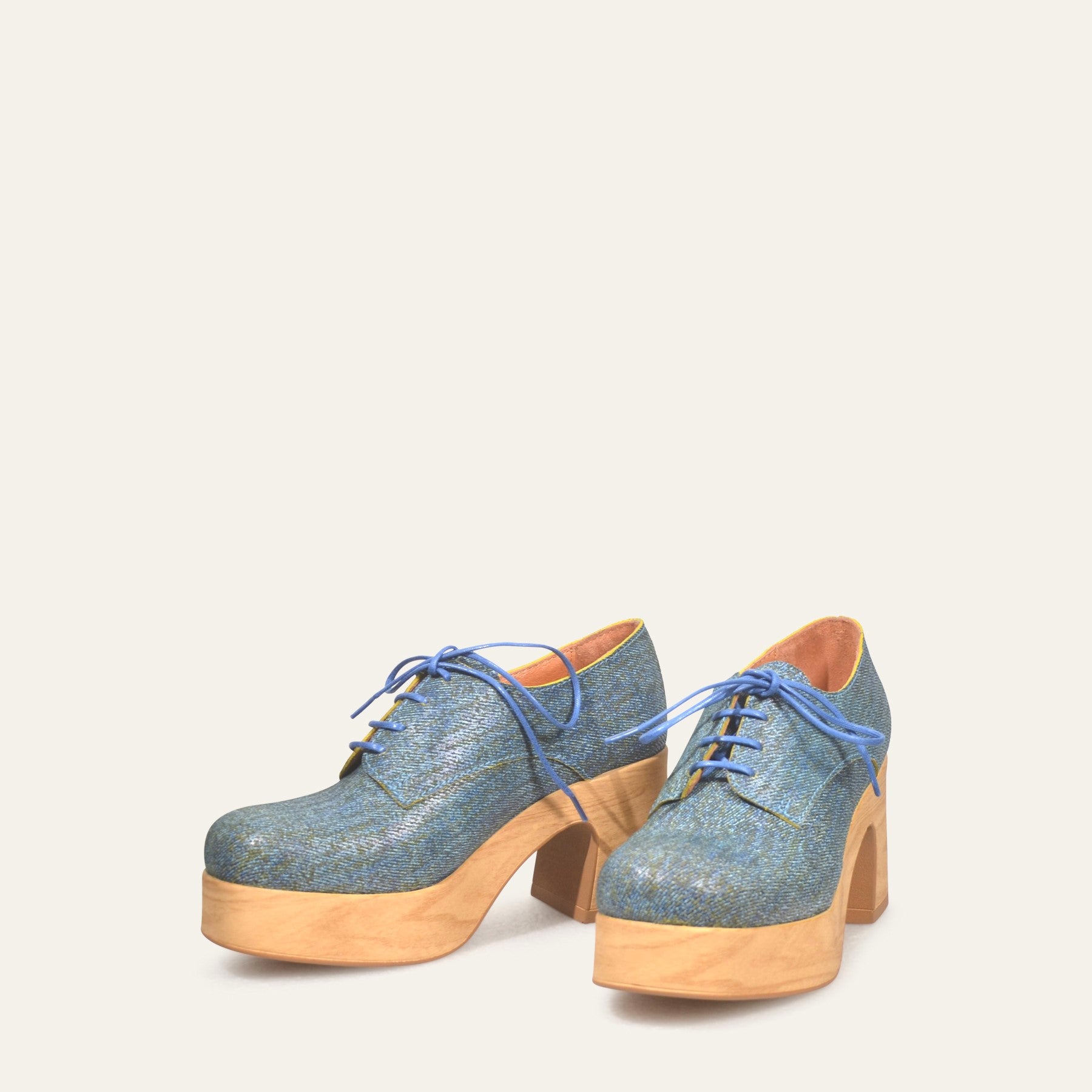 Blue denim platform shoes with wooden soles on a white background